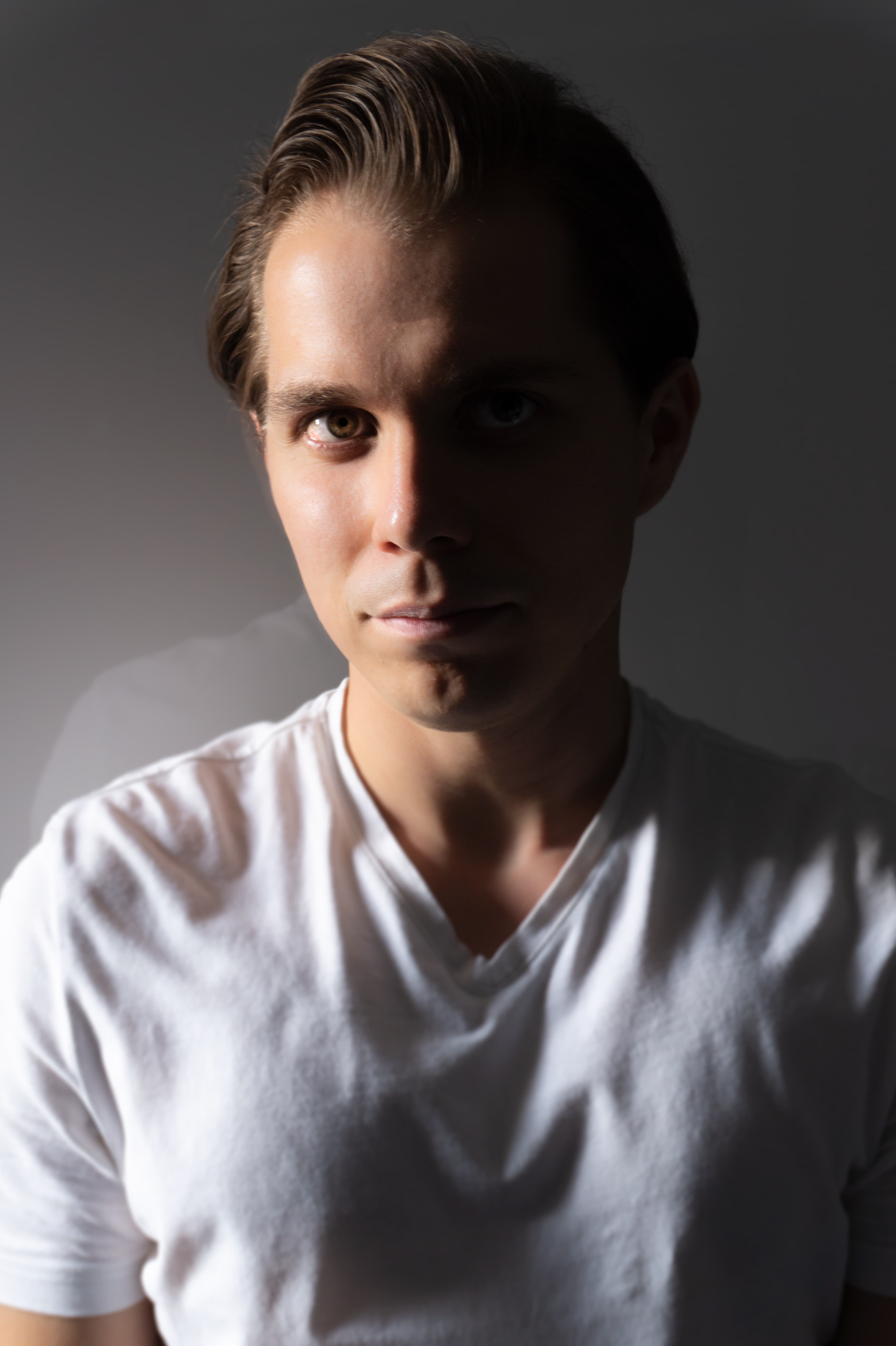 In reality, I'm nicer than I look in this picture. I assure you! Profile picture where I'm in a white t-shirt on gray gradient background. Half of my face is in the shadow. The other half is correctly illuminated.